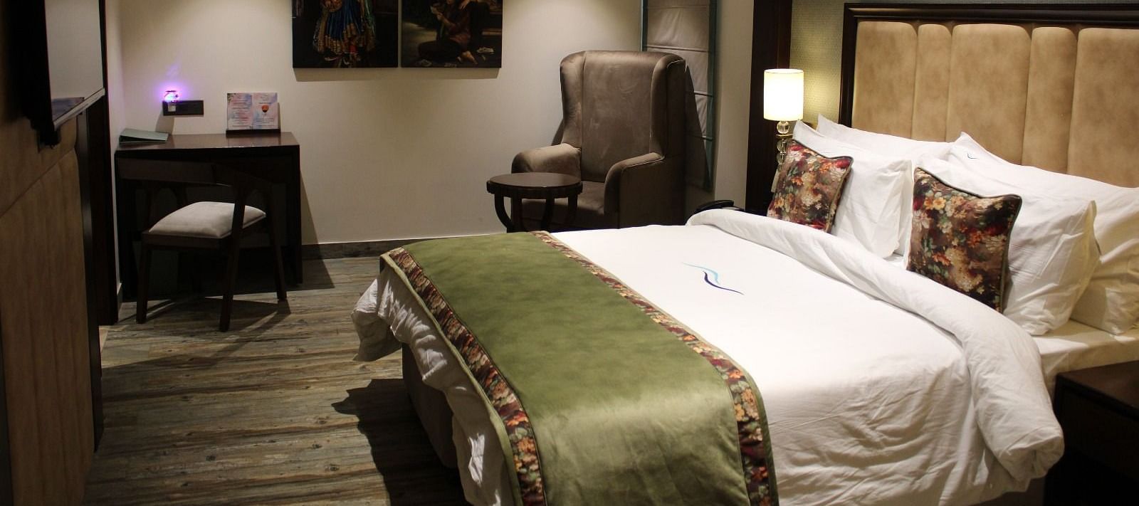 Side view of a bedroom featuring a working table, a chair, and portraits adorning the wall at BluSalzz Residence, Amritsar